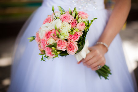 bride in white wedding dress holding a bouquet of white and pink roses in one hand horizontalの写真素材