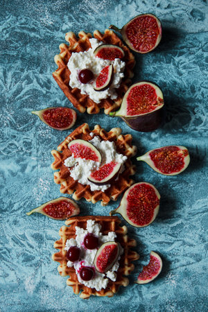 Overhead still life of belgian biscuit waffles with cottage cheese, fresh figs and cherry. Healthy...