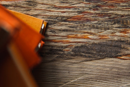 A stack of paper books in orange color on textured wooden surface. Autumn mood concept. Time to...