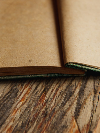 Open kraft notebook made of recycled paper on textured wooden table. Blank pages for writing