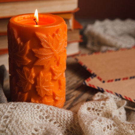 Autumn cozy still life of big orange candle, pile of books and vintage kraft envelopes.の写真素材