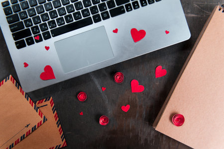 Online dating concept. Laptop with red paper hearts. Distance relationship on the internet.