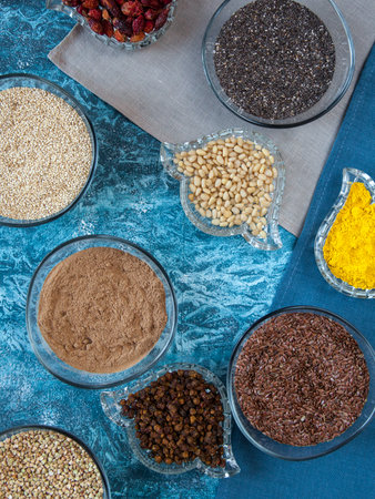 Superfoods in glassware on blue background. Bright colorful flat lay of healthy food products.の写真素材