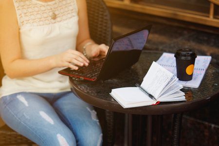 Girl copywriter sitting on cafe terrace with coffee. Woman freelancer writing outdoors.