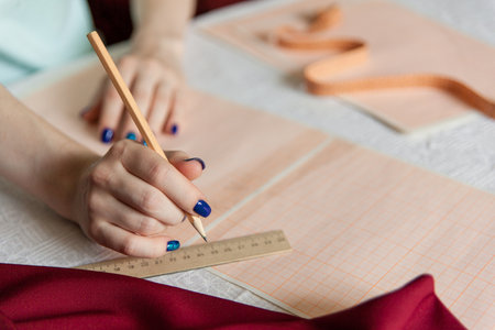 Sewing hobby background. Female hands holding a pencil. Cloth pattern building process.の写真素材