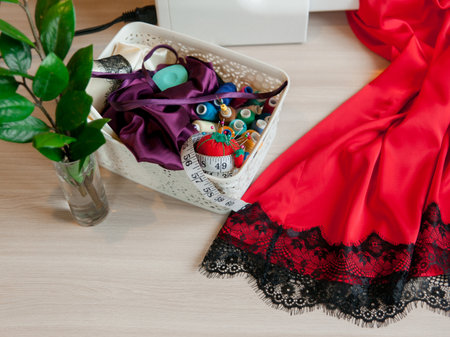 An attractive young woman sits at a table and sews silk underwear on a sewing machine. Concept of female small business at home.の写真素材