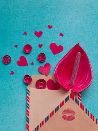 Overhead flat lay valentine day background. Red paper hearts and flowers handmade, kraft envelope letters with kiss print on blue texturred background. Bright inspiration for holiday of love.の写真素材