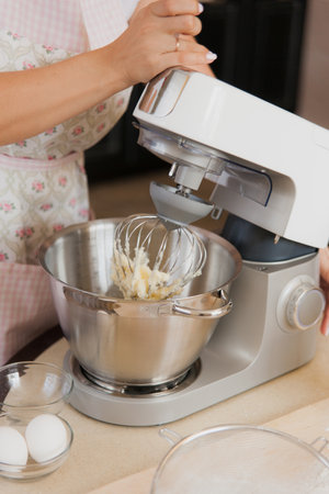 Female hands working with a food processor. Cooking process, making a dough with electric modern...