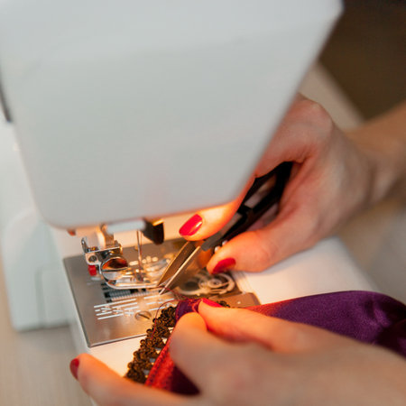 Female hands on sewing machine. Process of silk lingerie making. Close up of seamstress work.の写真素材