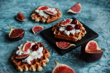 Still life of belgian biscuit waffles with cottage cheese, fresh figs and cherry. Healthy vegetarian breakfast.の写真素材