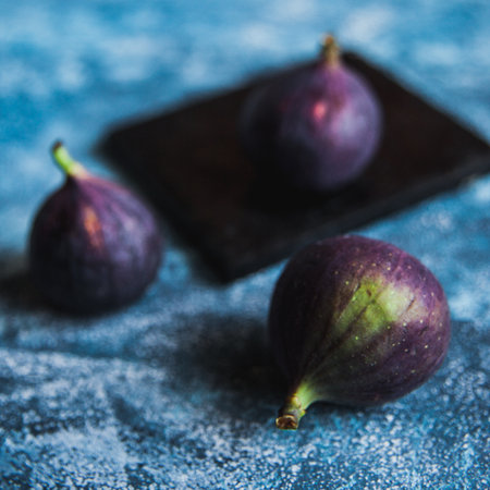 Fresh figs lying on black slate on blue surface.の写真素材