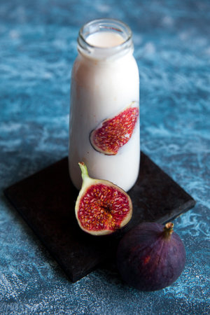 Still life of smoothie with fresh figs in glass bottle. Healthy vegetarian breakfast.の写真素材