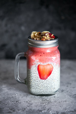 Layered chia pudding and strawberry-banana smoothie with berry slice and muesli. Vegan healthy diet concept.の写真素材
