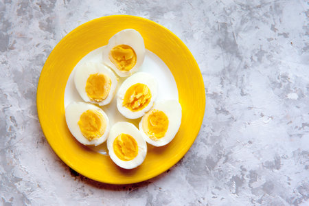 Halfs of three hard boiled eggs lying on a yellow plate