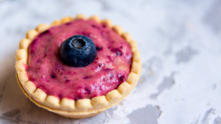 Sweet mini tartlet with cream and berries on white textured background. Simple dessert snack recipe with blueberry. Summer food conceptの写真素材