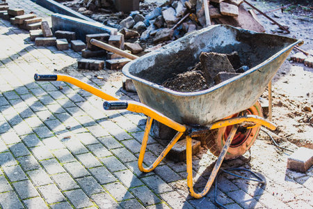 Construction wheelbarrow with concrete blocks on a Paving stone for repair sidewalk in a park.の写真素材