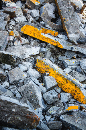A pile of construction debris made of concrete, bolts and stones with peeling yellow paintの写真素材