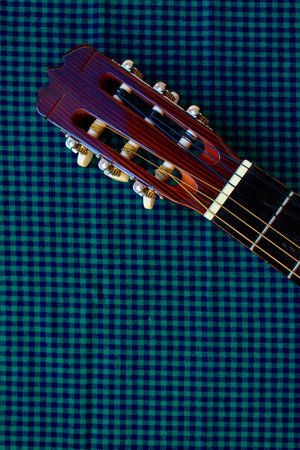 Acoustic classic guitar head on cozy plaid background. Folk country music concept.