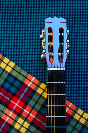 Acoustic classic guitar head on cozy plaid background. Folk country music concept.の写真素材