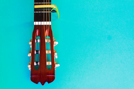 Acoustic classic guitar head on blue background. Simple musical instrument with copy spaceの写真素材
