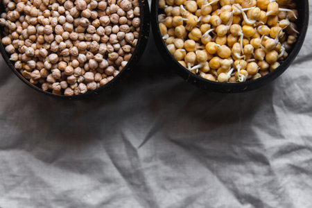 Sprouted and dry chickpea in wooden bowls on rustic linen textile. Bean sprouts raw. Source of protein for vegan healthy dietの写真素材