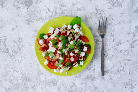 Healthy vegetarian salad of red tomatoes, white cheese and fresh greens, seasoned with sauce. Salad...