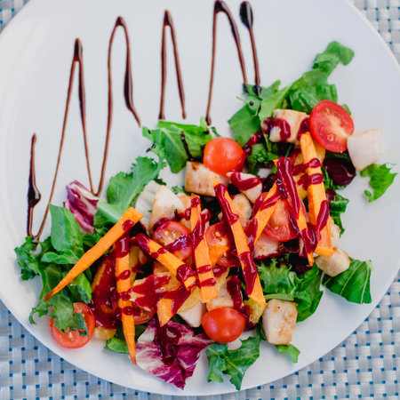 Colorful salad made of chicken, oranges, tomatoes and carrot eith lettuce.の写真素材