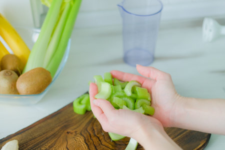 Cut green celery stalk slices in female hands. Healthy vegan diet.の写真素材