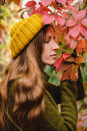 Girl in mustard yellow knit hat and marsh green wool sweater walking among colorful ivy in autumnの写真素材