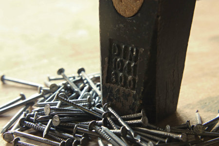 Hammer head with the couple of nails on wooden board