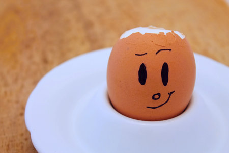 Egg with face with broken shell on white plateの写真素材