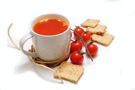 Tomato soup in a cup with tomato shrub and crackers around isolated on white backgroundの写真素材