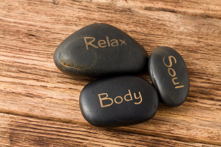 Photo of three lava stones for massage placed on old wooden board with very nice groovy texture.