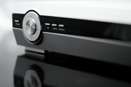 Photo of volume, channel controller on silver dvd player with mirror reflection in black mat below the equipment.の写真素材