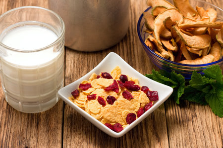 Horizontal photo of modern square bowl full of cornflakes with fruit. Glass of milk and other bowl...