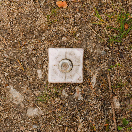 Square photo of border marker. Plastic border marker separating land plots. Plastic cube in soil. Marker placed in the earth. Dividing mark of land. Boarder between land plots.の写真素材