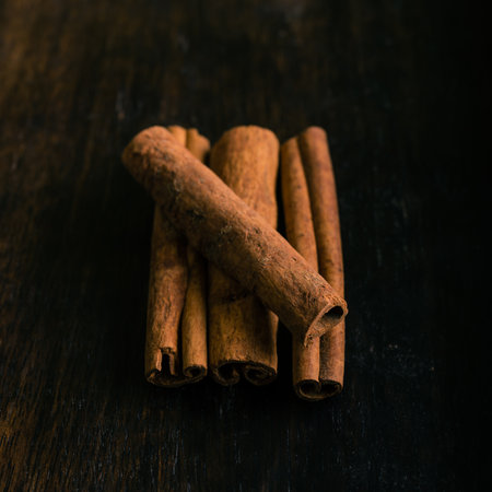 Square photo of four pieces of cinnamon spice which is placed on a pile with one cross the others....