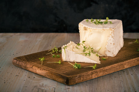 Horizontal photo with unusual camembert. Cheese with cube shape with cress on vintage chopping board...