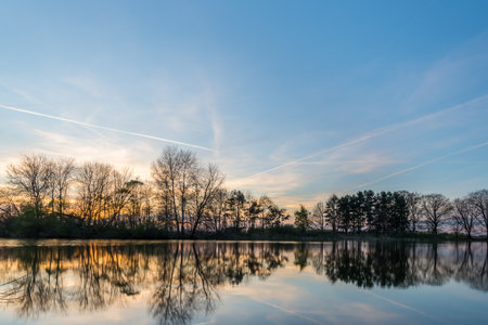 Horizontal photo of landscape after sunset with several trees captured in early spring time on the...