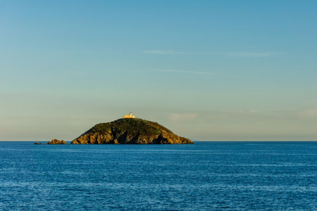 Horizontal photo with evening view on the rock with ancient historic fort in Mediterranean Sea between elba island and Italian coast. The sky is almost clear and blue.の写真素材