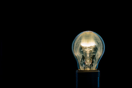 Horizontal photo of single glass bulb placed in the socket on black background. The fire and flame inside is caused by burning wire. The bright smoke is filling the inner space. Edge of object is blue.の写真素材