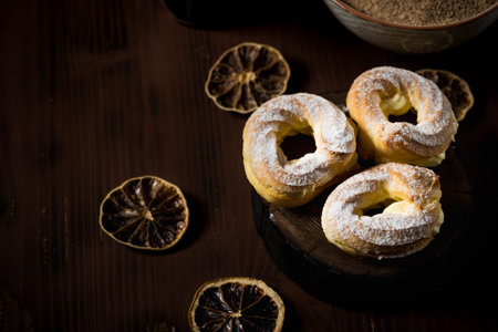 Horizontal photo of three cream puffs filled by cream and covered by powder and cinnamon sugar. Few...