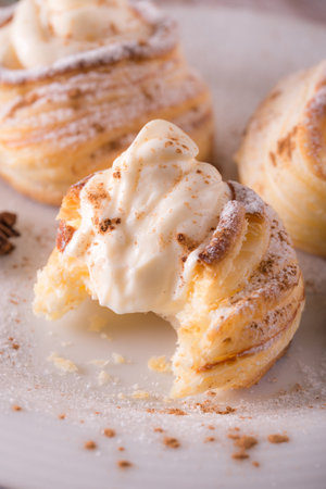 Vertical photo with sweet dessert. Dessert is made from puff pastry filled by curd cheese and powdered by cinnamon. Star anise is on plate with desert on wooden board.の写真素材