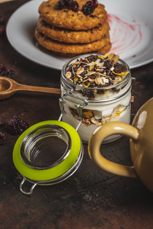 Glass full of white yogurt and muesli on dark wooden boardの写真素材