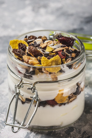 Glass full of white yogurt and muesli on light wooden boardの写真素材