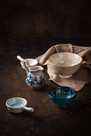 Vertical photo of few ceramic bowls with various shapes and colors. Bowls are placed on dark wooden...