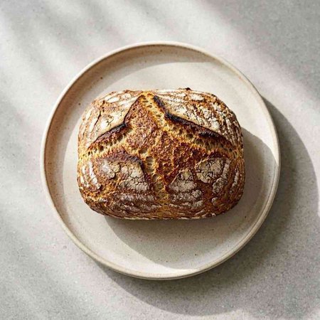 Loaf of rye bread on a plate on a light background.