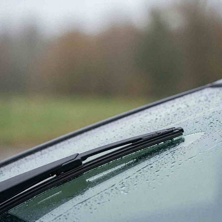 A closeup of a windshield wiper on a car in the rain