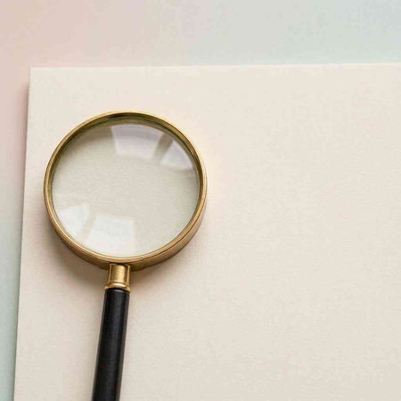 Magnifying glass on a white paper background. Place for your text.