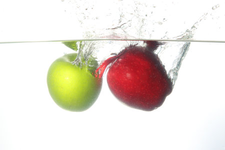 Close up apple fell into the water, white background.の写真素材